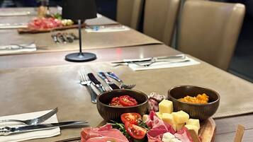 Een eettafel met diverse soorten eten, zoals vleeswaren, kazen en olijven, gepresenteerd op een houten plank.