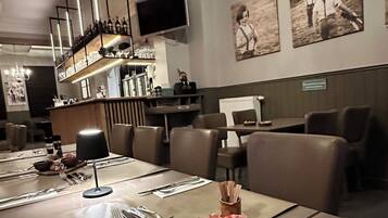 Ein Essbereich mit einem Holztisch, gedeckt für eine Mahlzeit, inklusive einer Platte mit verschiedenen Fleisch- und Käsesorten, und einer darüber hängenden Chandelier.