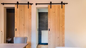 A room with a wooden sliding door, a white bed, a table, and a chair. - 't Oud gemeentehuis Poelkapelle (Langemark-Poelkapelle)