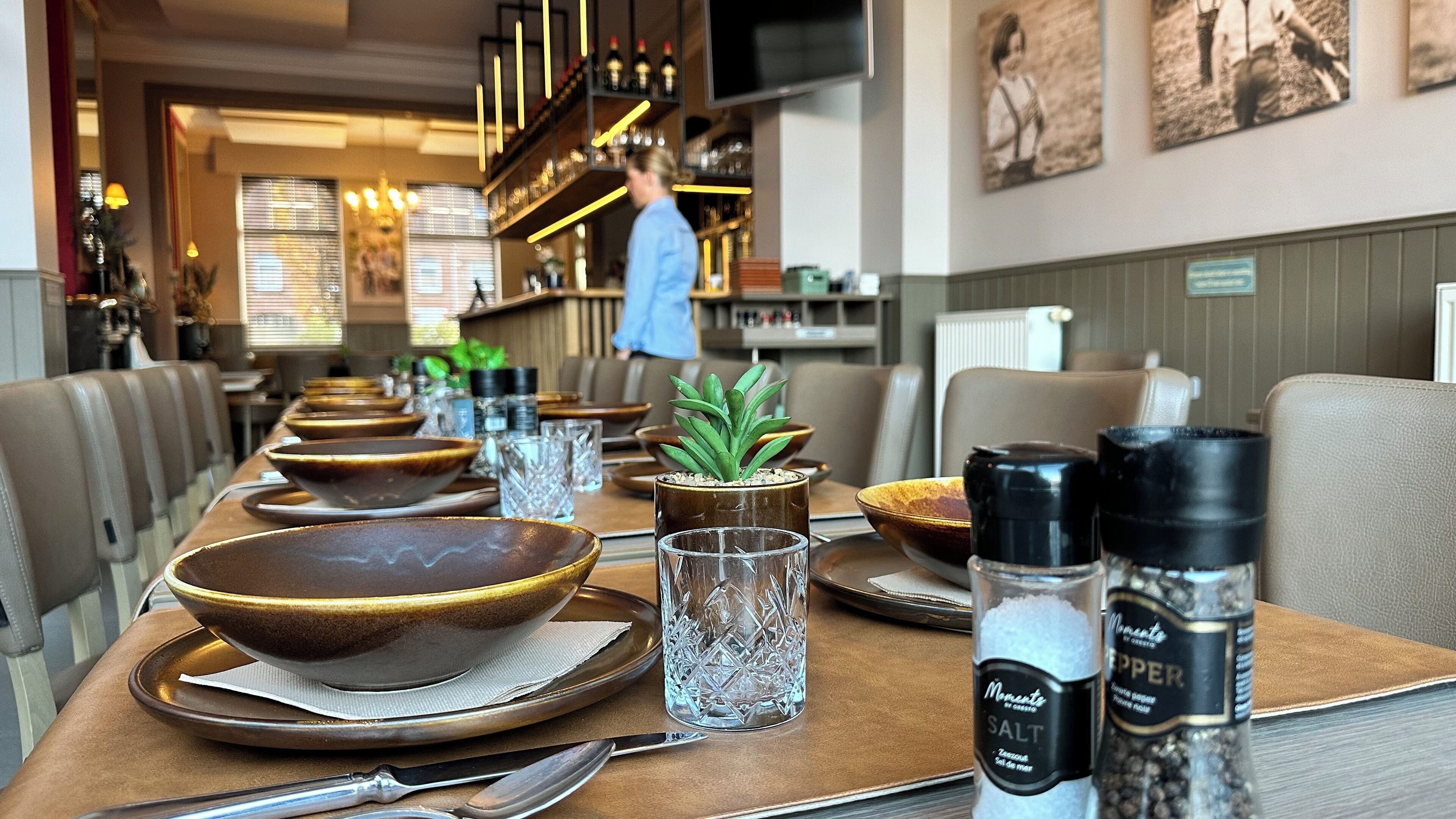 Une table à manger dressée avec des bols, des verres et des salières.