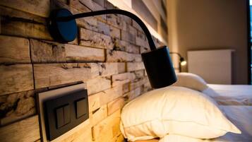 Un lit avec une literie blanche et une tête de lit en bois agrémentée d’un luminaire au design moderne.