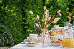 Una tavola apparecchiata con tazzine da tè, un vaso con fiori secchi, una caraffa di tè e una pagnotta di pane.