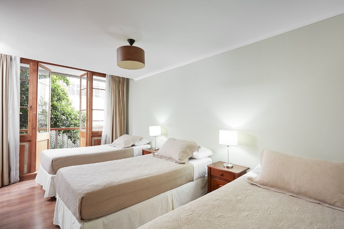A hotel room with two beds, a balcony, and a ceiling light.