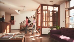 A spacious living area with a wooden floor, a purple sofa, and a staircase leading to an upper level. - Hotel Loreto (Santiago)