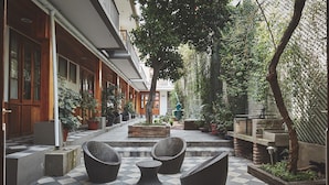 A courtyard with checkered flooring, wicker furniture, potted plants, and a water feature. - Hotel Loreto (Santiago)