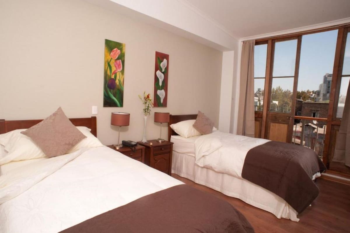 Una habitación de hotel con dos camas, un ventanal grande y obras de arte en la pared.