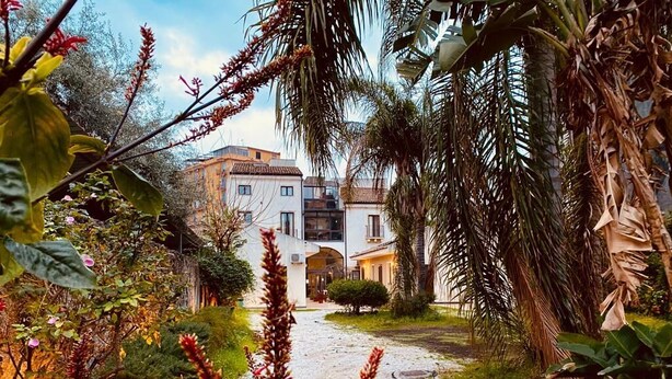 A pathway leading to a building with a white facade and multiple windows. - Hotel La Palma (Catania)