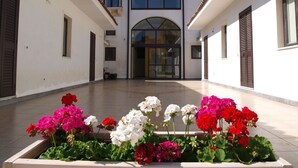 A courtyard with a central entrance, surrounded by white walls and a tiled floor. - Hotel La Palma (Catania)