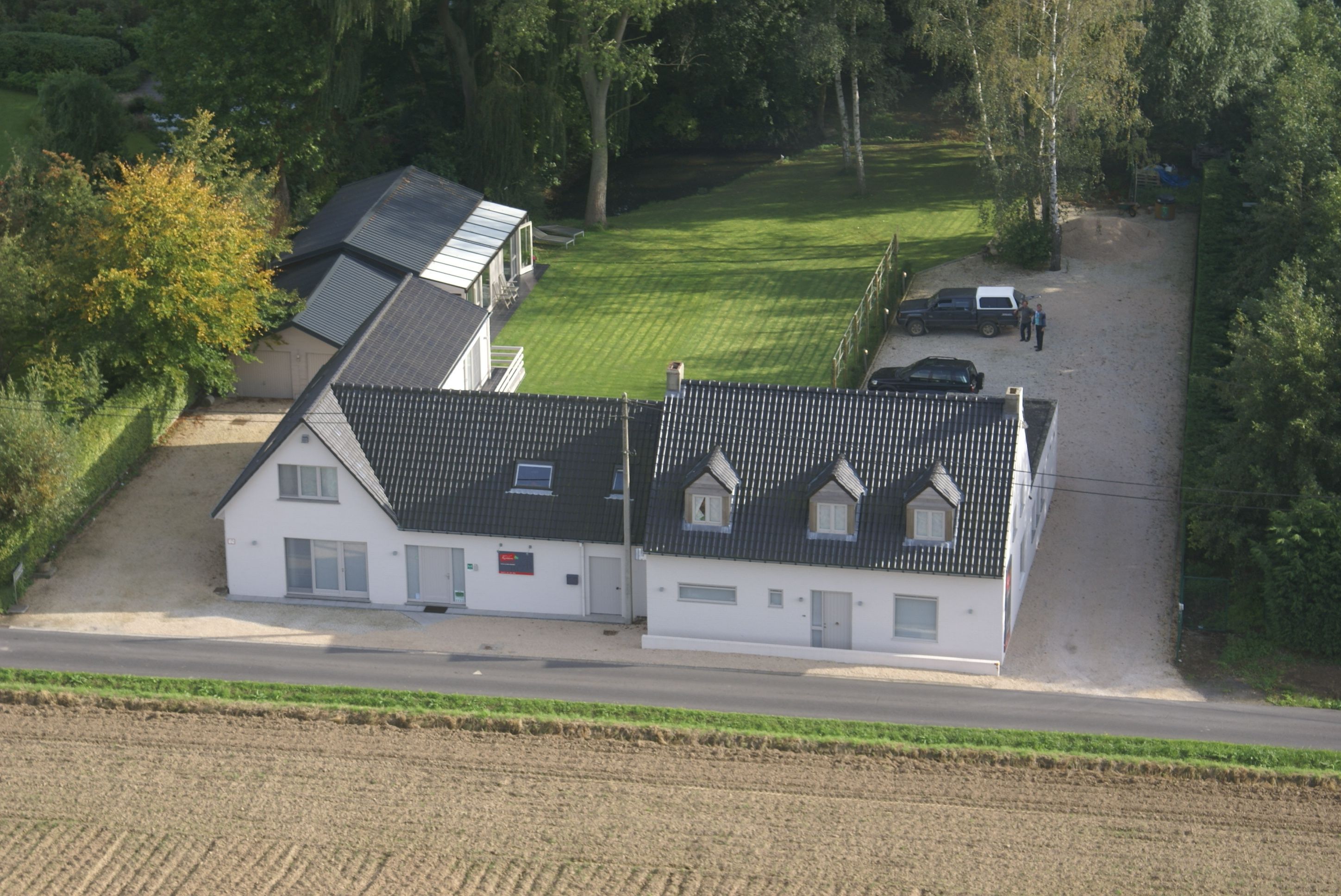 A two-story house with a sloped roof, a driveway, and a lawn.