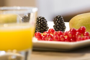 A table with a glass of orange juice, blackberries, red currants, and a green fruit, possibly a pear or apple. - Maison Kerkhove (Avelgem)