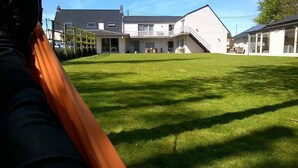 A grassy lawn with a building in the background. - Maison Kerkhove (Avelgem)