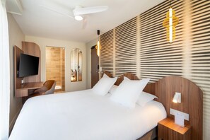 A hotel room with a large bed, a TV mounted on a wooden cabinet, a desk with a chair, and a wall-mounted light fixture. - Best Western Hotel Le Crystal Dinard (Dinard)
