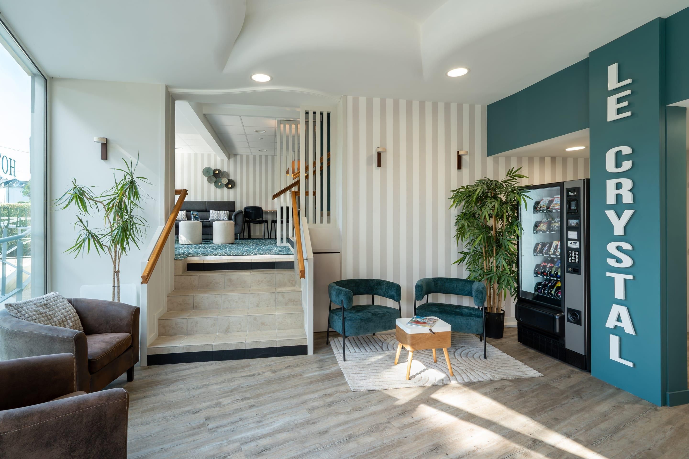 Un interior moderno con una escalera, una zona de estar y un dispensador de productos etiquetado 'LE CRYSTAL'.