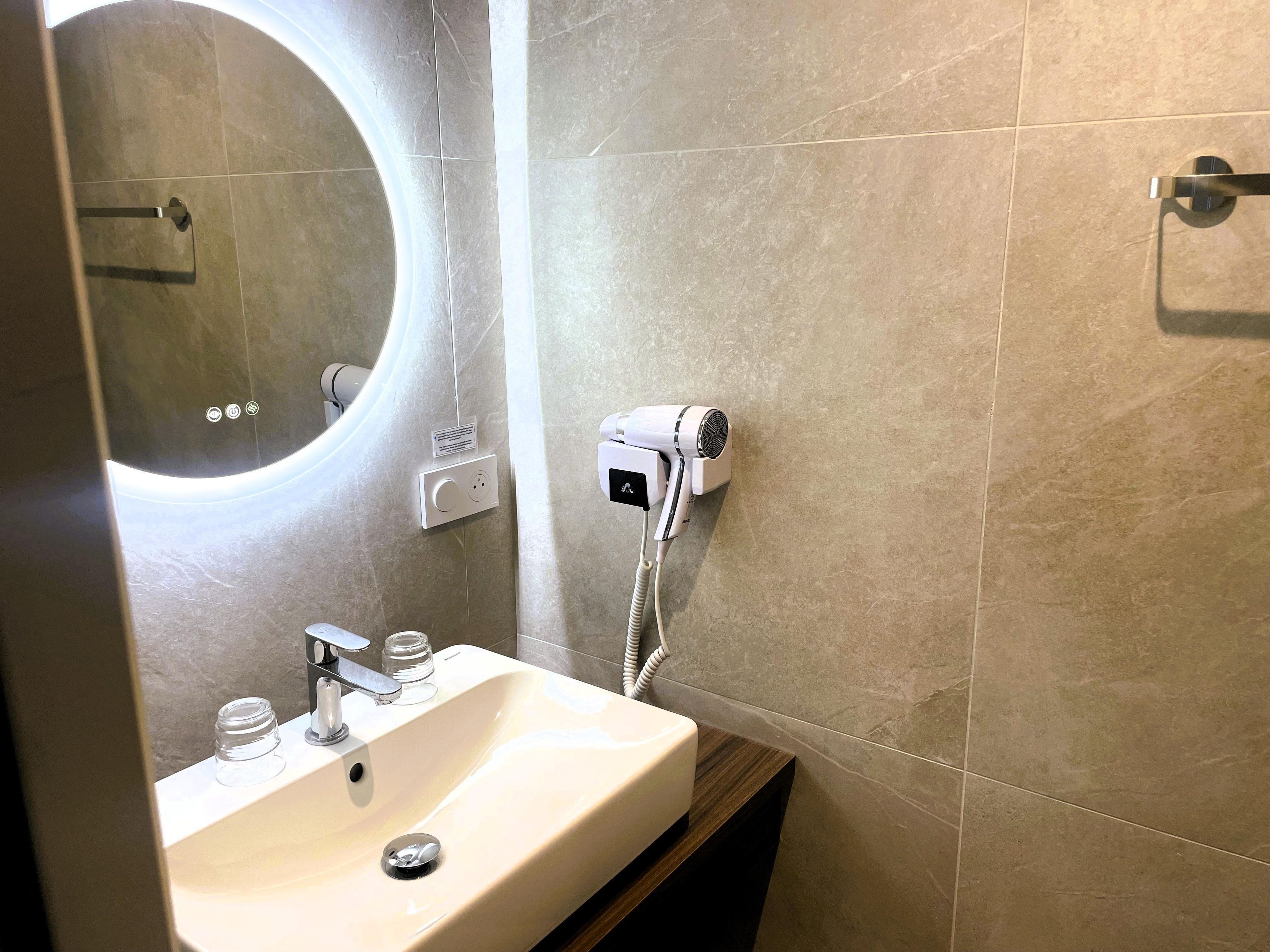 Un baño con lavamanos, espejo, toallero y secador de pelo.