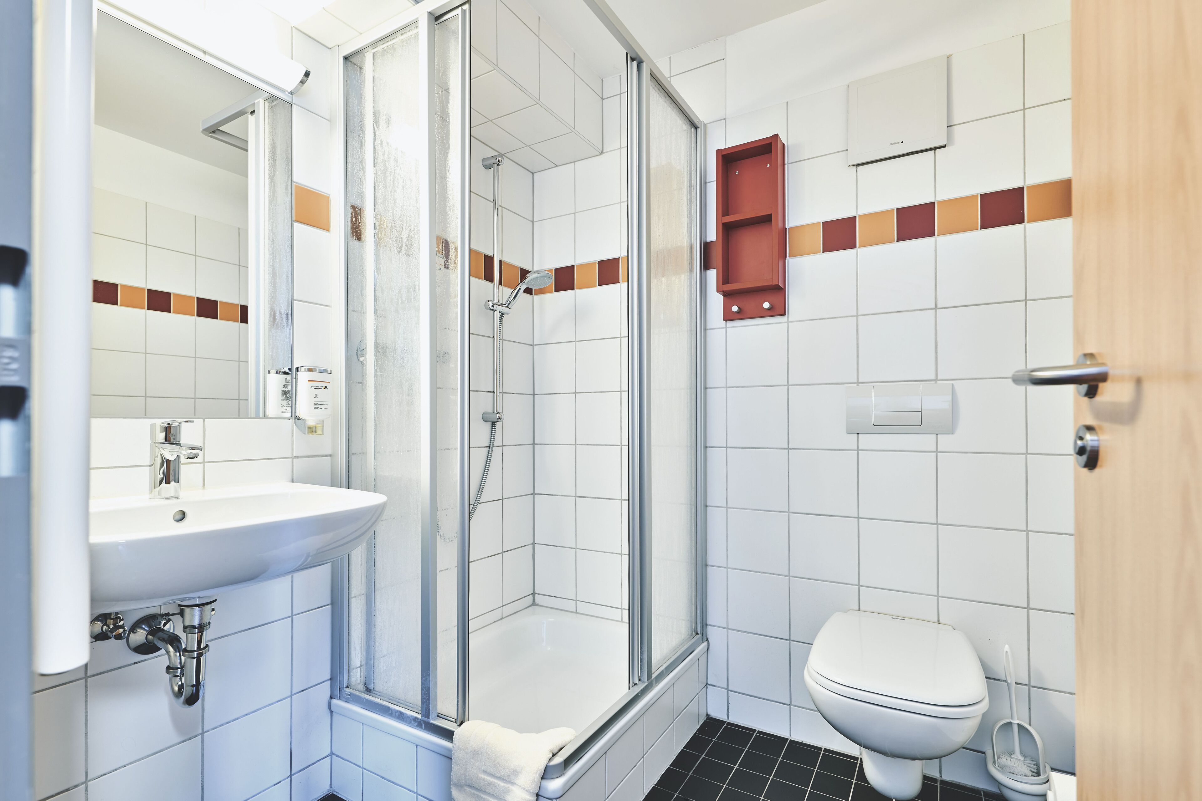 A bathroom with a glass-enclosed shower, a white sink, and a toilet.