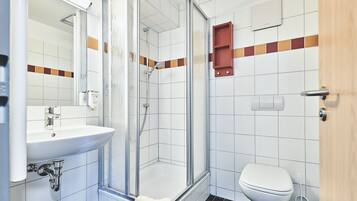 A bathroom with a glass-enclosed shower, a white sink, and a toilet.