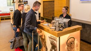 Un comptoir d’accueil avec un plan de travail en bois, une grande fenêtre et un écran fixé au mur.