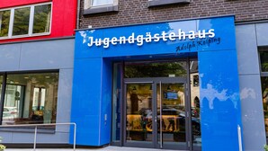 Un bâtiment à la façade bleue, sur lequel on peut lire l’inscription « Jugendgästehaus Adolph Kolping ».