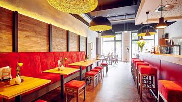 Un restaurante con paredes de madera, asientos rojos e iluminación colgante.