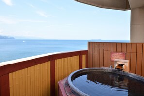 Una terraza de madera con un baño termal y vista al mar.