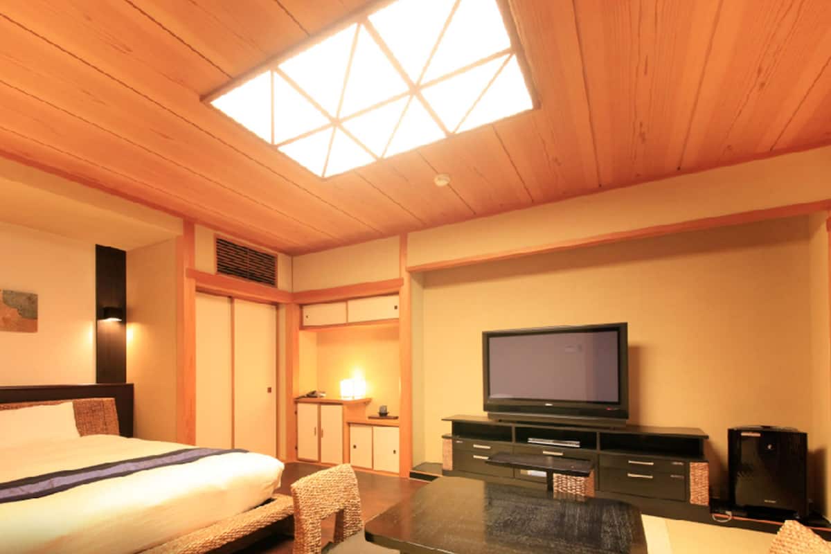 Ein Hotelzimmer mit einem Bett, einem Fernseher, einem Schreibtisch und einem Schrank.