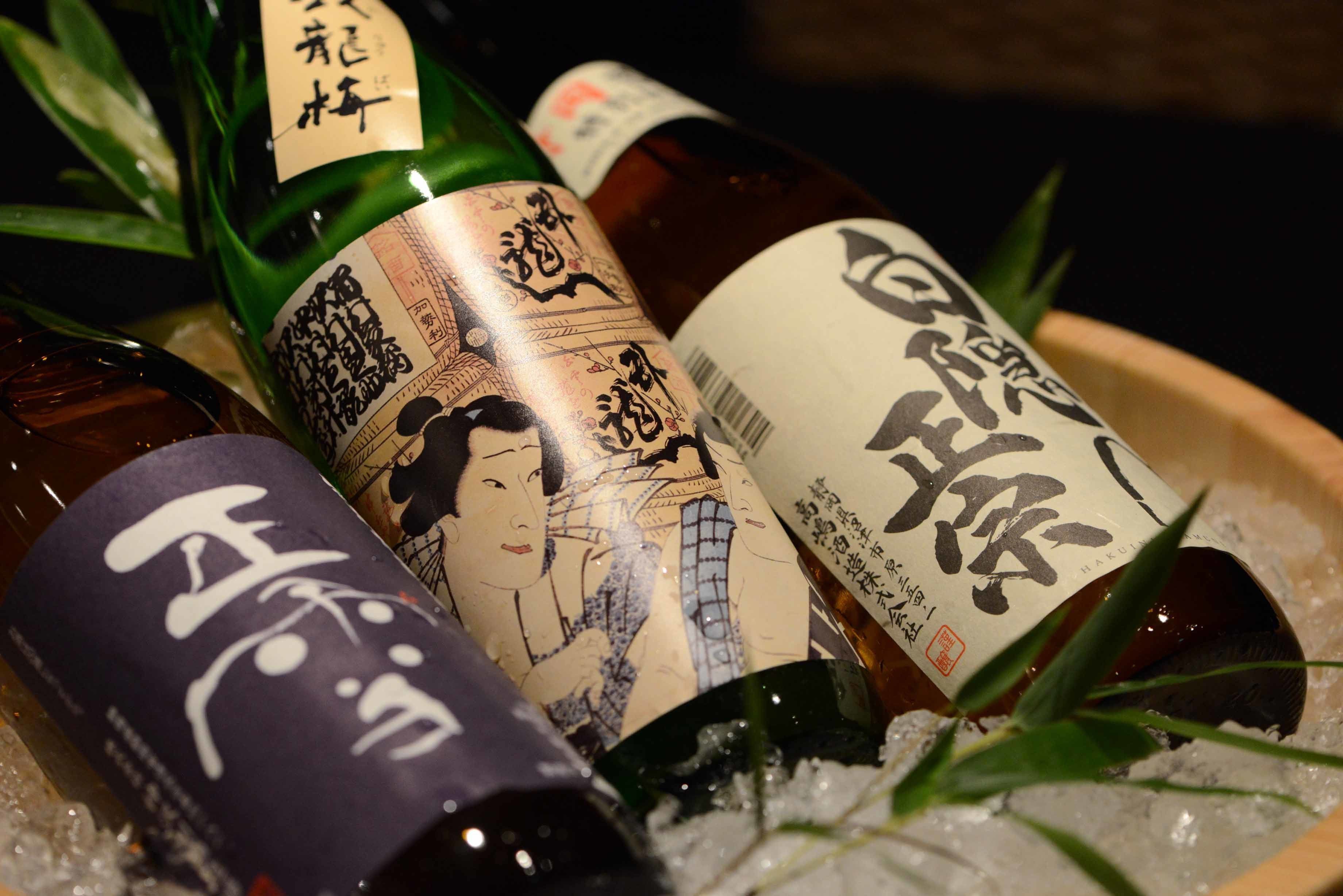 Three bottles of sake on ice with traditional Japanese labels.
