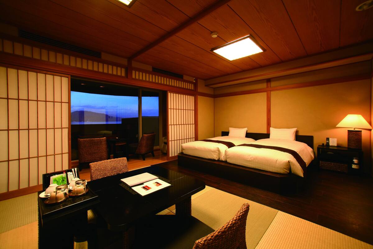 Ein Hotelzimmer mit einem großen Bett, einem Schreibtisch mit Stuhl und Bergblick durch eine Schiebetür.