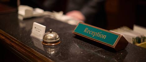 Un comptoir d’accueil avec une plaque nominative indiquant « Réception » et une clochette.