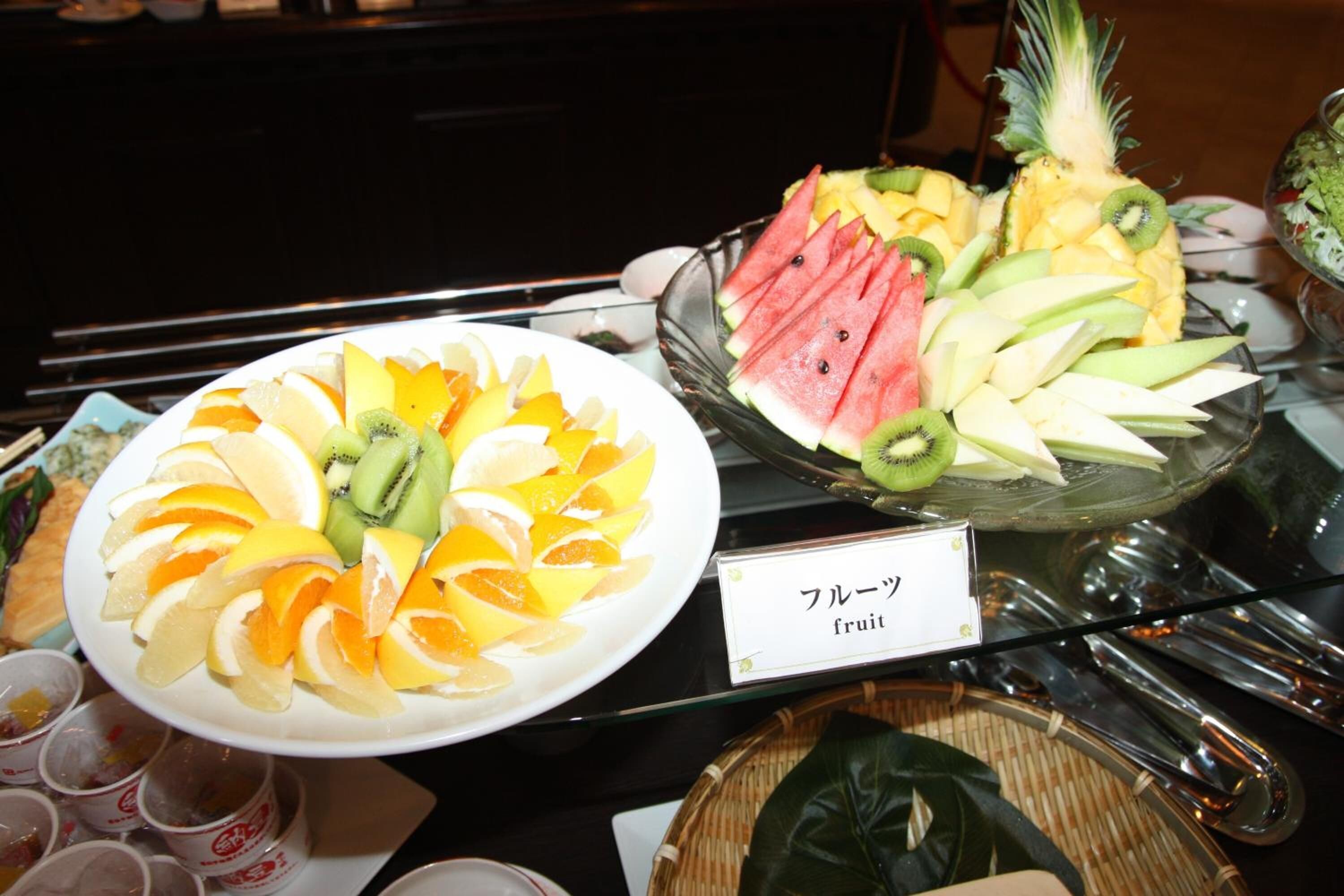 A buffet table with various fruit platters, including sliced oranges, kiwi, watermelon, and pineapple.