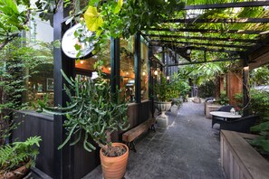 An outdoor patio area with a wooden bench, potted plants, and a pergola structure. - Abloom Exclusive Serviced Apartments (Bangkok)