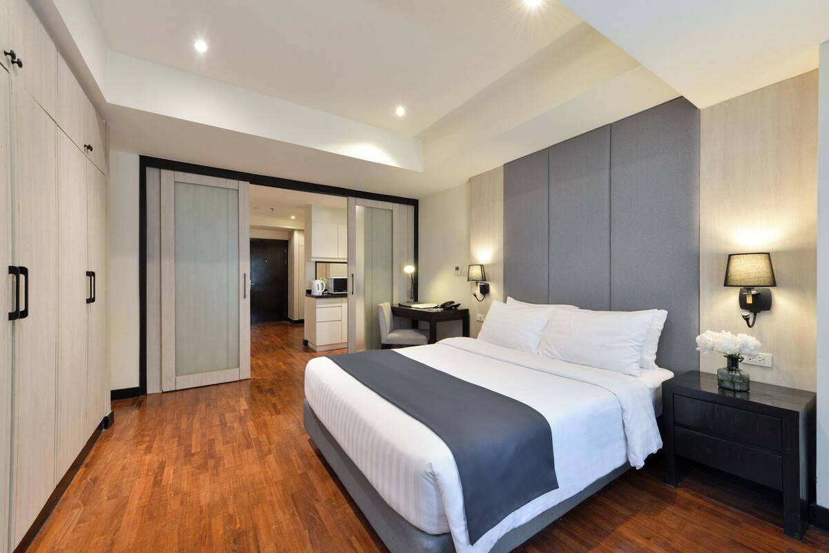 A modern hotel room with a large bed, a desk, and a walk-in closet.