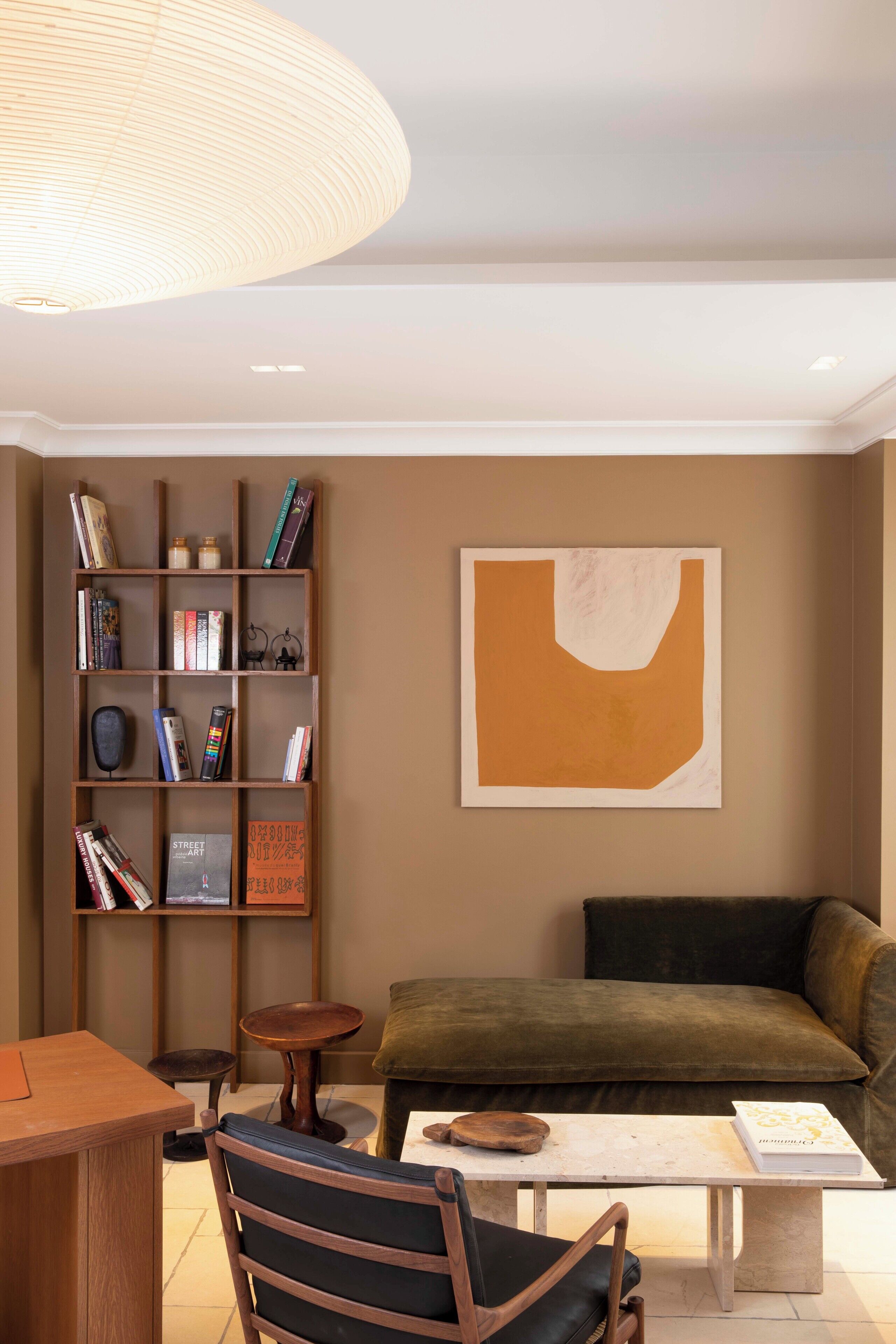 A modern living room with a bookshelf, a sofa, a coffee table, and a pendant light.