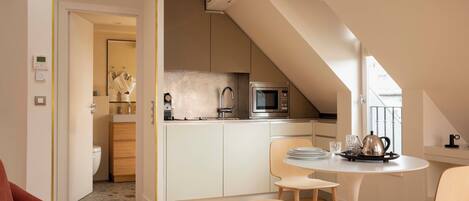 A modern kitchen with a microwave, sink, and cabinets, a dining area with a table and chairs, and a visible bathroom with a toilet.