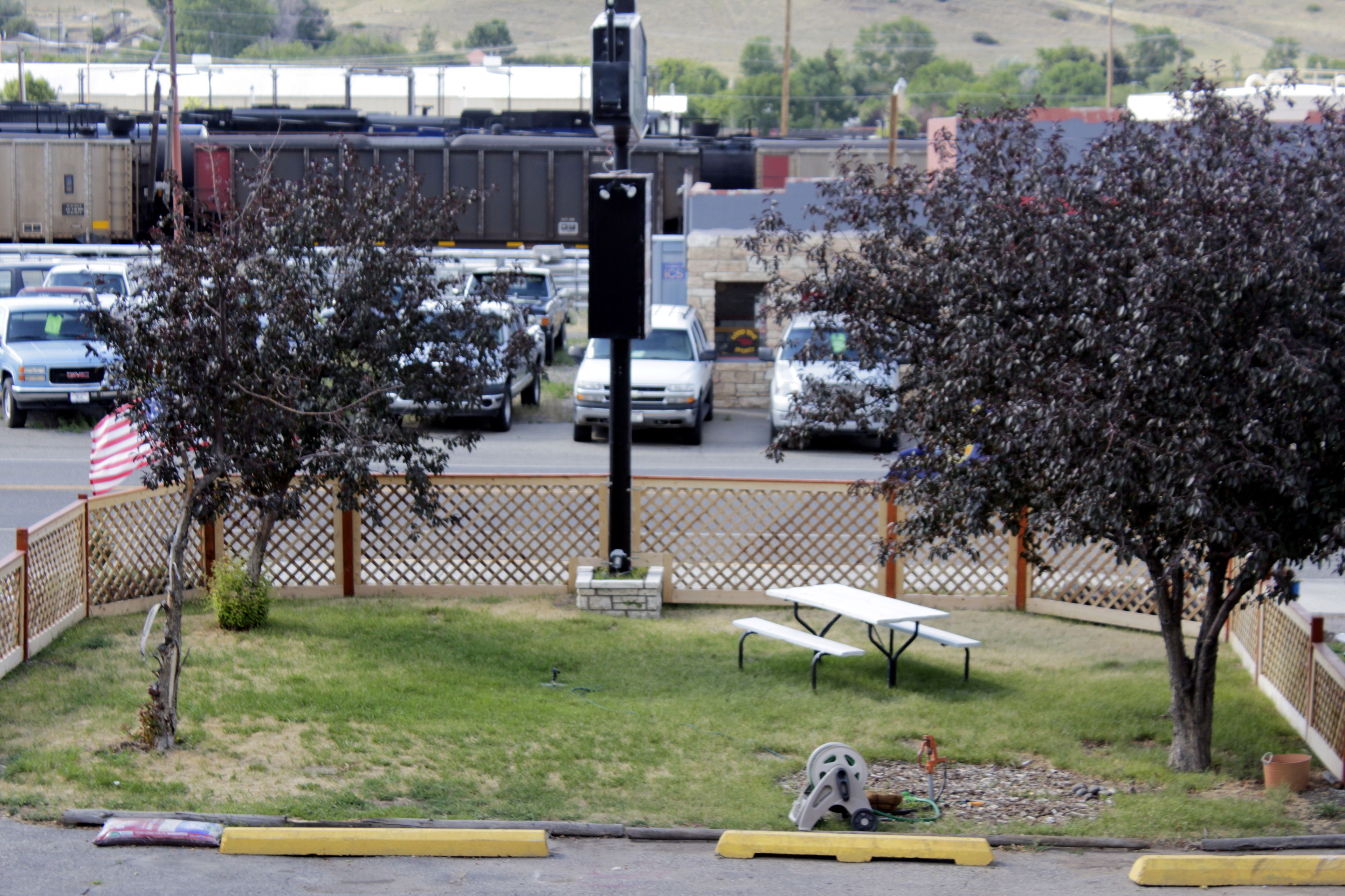 A parking lot with cars, a picnic table, and a small statue.