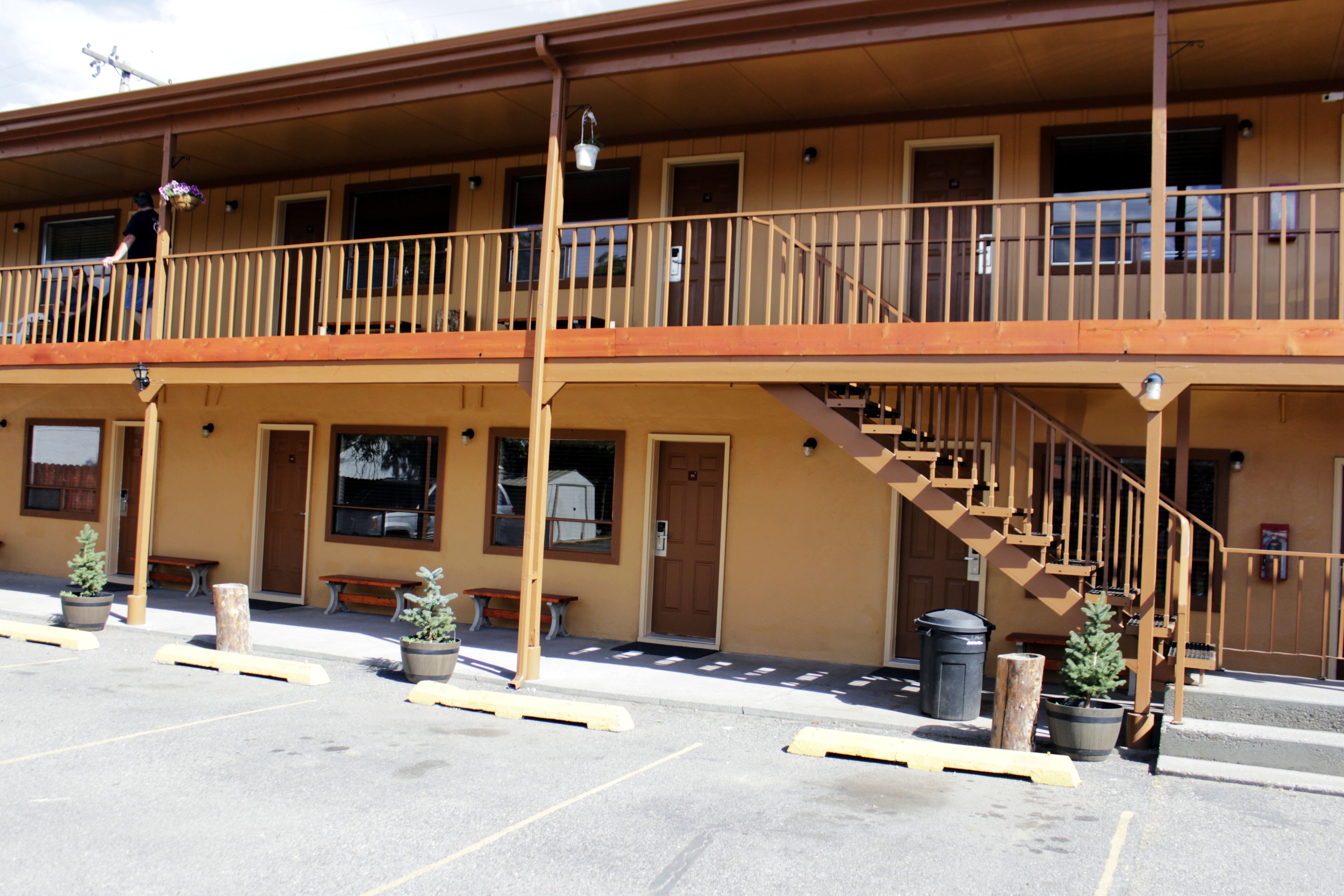 A two-story building with a balcony, outdoor seating, and a staircase.