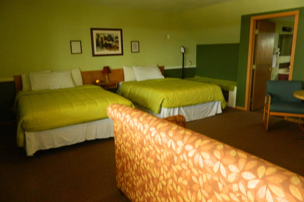 A hotel room with two beds, a chair, and a painting on the wall.