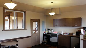 A compact kitchen with wooden cabinets, a coffee maker, and a microwave. - Country Motor Inn (Livingston)