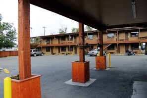 A motel with a two-story structure, outdoor parking, and a covered area with wooden pillars.