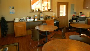 A kitchen with a dining area, wooden cabinets, a window, and a refrigerator. - Country Motor Inn (Livingston)