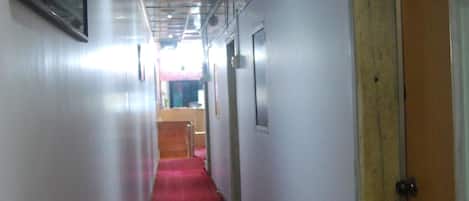 A corridor with a red carpet, white walls, and doors on both sides.