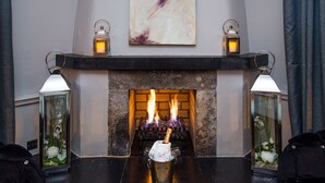 A fireplace with burning logs, a candle holder with a lit candle, and two wall-mounted lanterns. - Hotel Kilkenny (Kilkenny)