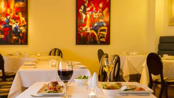 A dining table set with plates, glasses, and cutlery, with a candle and a painting on the wall.