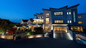A modern hotel with a well-lit entrance, outdoor seating area, and a staircase leading to the main building. - Hotel Kilkenny (Kilkenny)