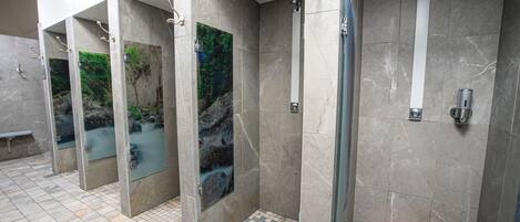 A public restroom with multiple stalls, each with a glass panel featuring a nature scene.