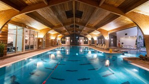 An indoor swimming pool with wooden beams, clear water, and a lifeguard chair. - Hotel Kilkenny (Kilkenny)