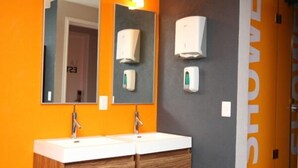 A modern bathroom with two sinks, a mirror, and wall-mounted soap dispensers. - Hostal La Buena Vida (Mexico City)