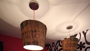 A reception desk with a marble top, a red wall with the text "LA BUENA VIDA," and two hanging lamps with text on them. - Hostal La Buena Vida (Mexico City)