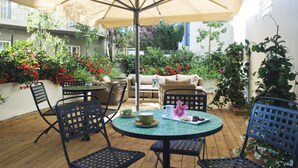 Un patio con una mesa redonda, sillas y una sombrilla grande.