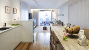 Una cocina moderna con encimera de madera, un comedor con una mesa larga y vistas al exterior a través de un ventanal.