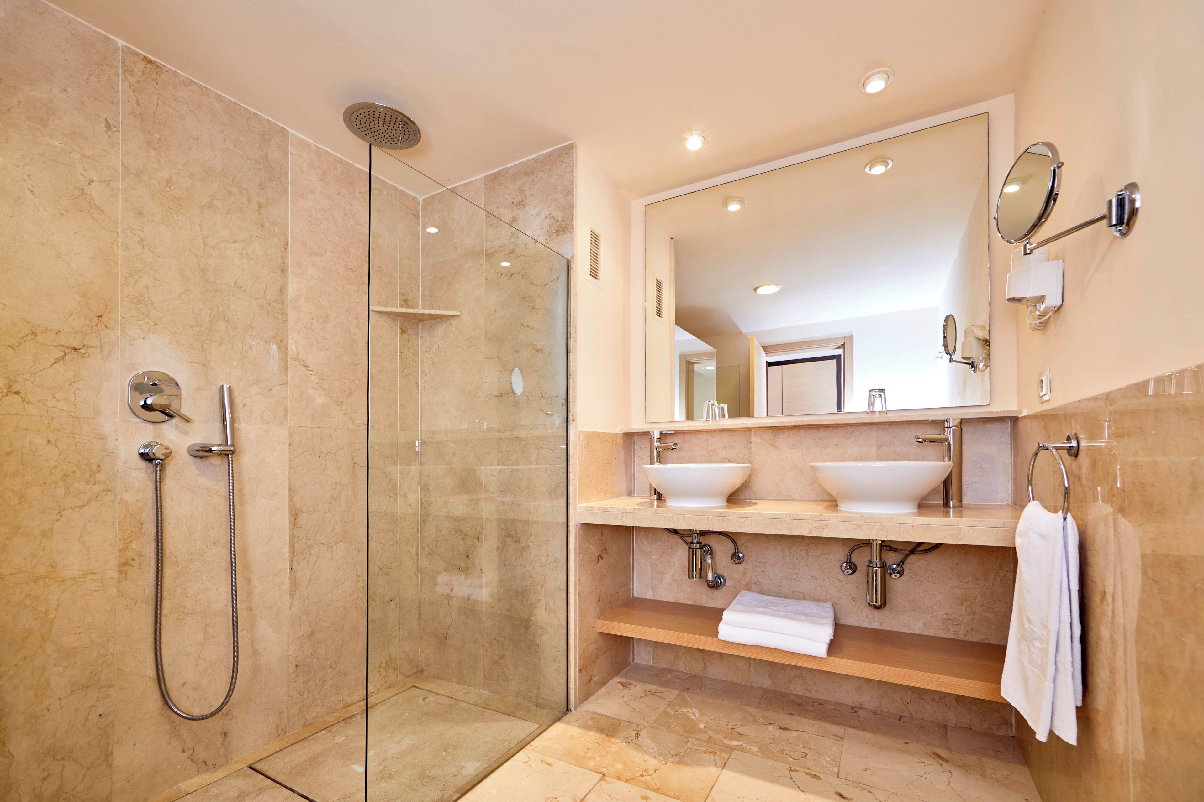 A modern bathroom with a glass-enclosed shower, two sinks, and a large mirror.